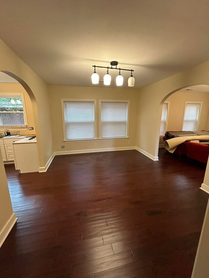 Finished open interior with dark wood flooring, windows, and connected rooms