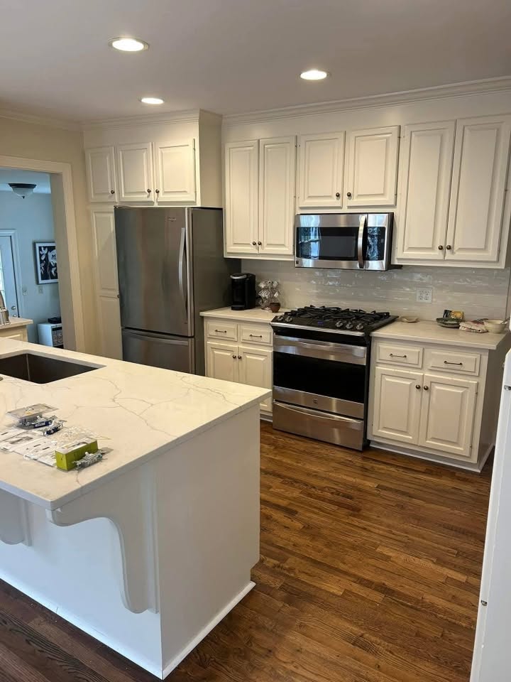 Finished kitchen with painted cabinets, quartz counters, stainless appliances, and wood flooring