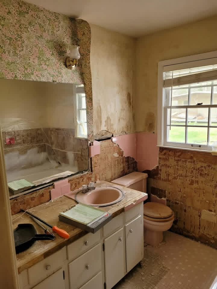 Bathroom in progress during strip-out with dated pink fixtures