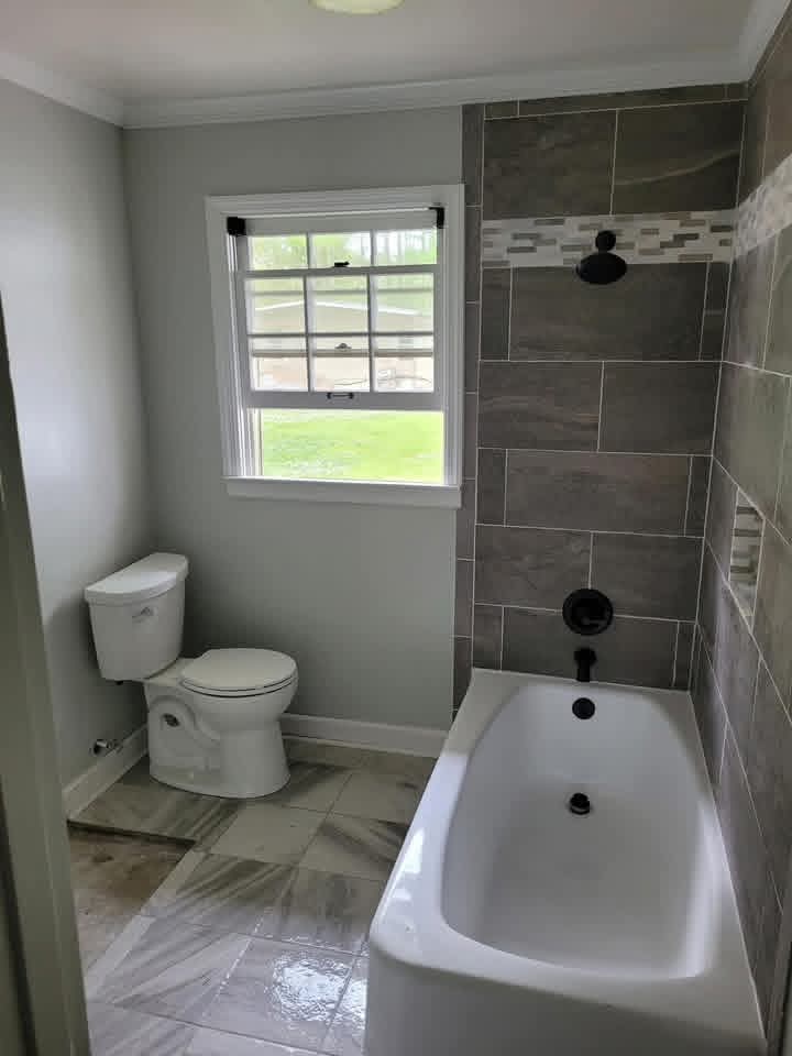 Bathroom with grey tile tub surround and black fixtures